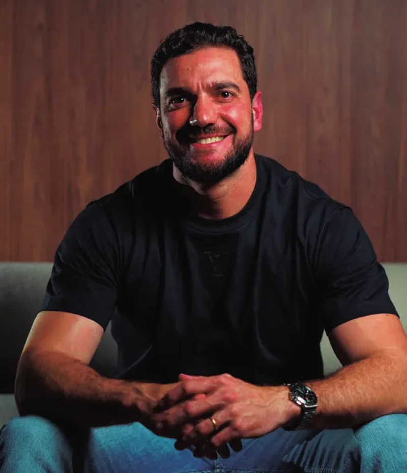 Matheus Artal sorrindo, sentado, de camiseta preta